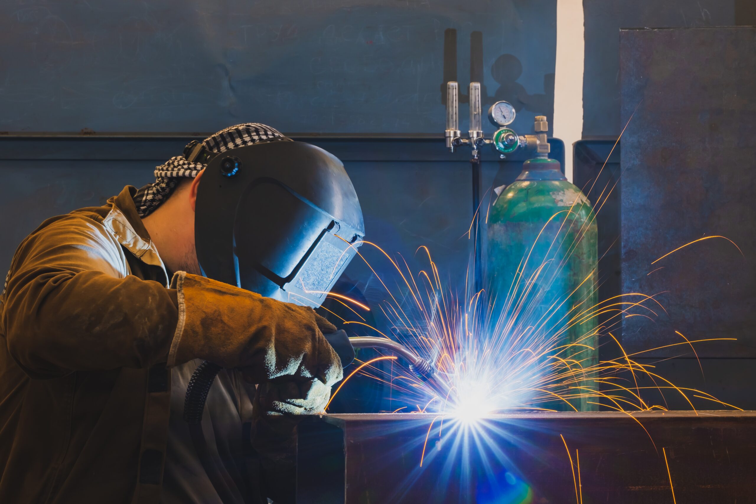 Bright welding arc as a welder fuses metal pieces together in a manufacturing setting.